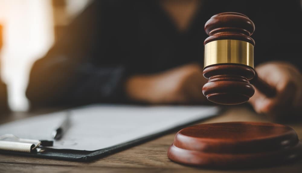 A judge's gavel poised above its block on a desk, symbolising a legal ruling or settlement.